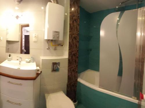 La salle de bains est pourvue d'un lavabo, de toilettes et d'une baignoire. dans l'établissement Mieszkanie 3 pokojowe Park Chopina, à Świnoujście