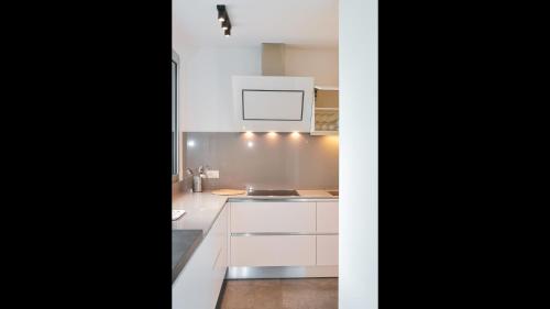 una cucina bianca con armadi bianchi e piano cottura di Front Lake Apartment Meli With View Feel Ticino Feel Home a Melide