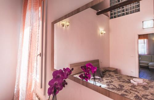 un espejo en una habitación con flores púrpuras en un jarrón en Ca' Laura - Murano Centro en Murano
