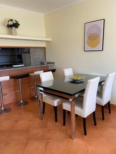 a dining room with a black table and white chairs at Condominio do Mar in Lagos