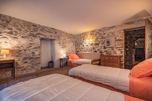 a bedroom with two beds in a room with stone walls at Sundrenched Relais de Poste in Serdinya in Serdinya