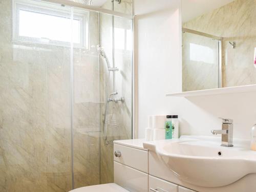 een witte badkamer met een douche en een wastafel bij The Lodge At Forbury Cottage in Kimbolton
