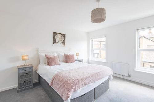 a white bedroom with a large bed with pink pillows at Stone's Throw in Deal