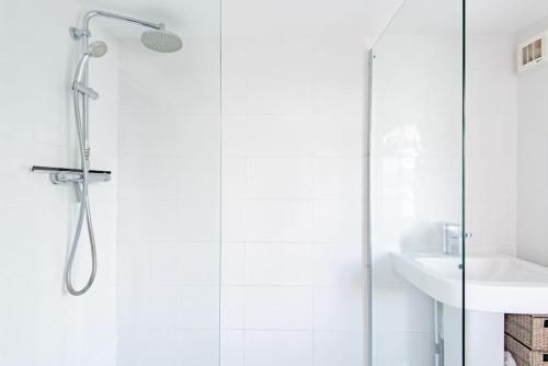 a white bathroom with a shower and a sink at Stone's Throw in Deal