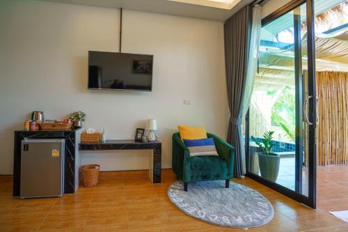 a living room with a green chair and a mirror at Phetra pool villas in Surat Thani