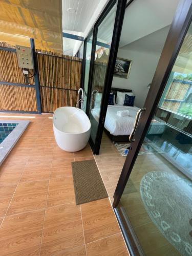 a bathroom with a tub and a bed in a room at Phetra pool villas in Surat Thani