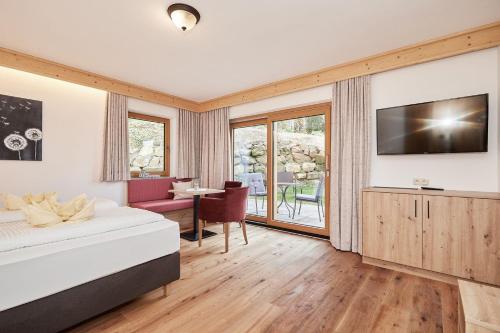een slaapkamer met een bed, een televisie en een bureau bij Landhotel Berger in Ainring