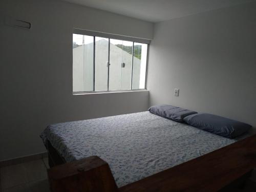 a bedroom with a bed and a window at Loft/APTO em Praia da Pinheira in Pinheira