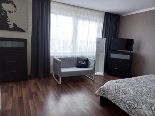 a bedroom with a bed and a chair and a television at Vienibas apartment in Daugavpils