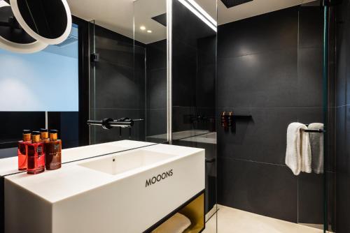 La salle de bains est pourvue d'un lavabo blanc et d'une douche. dans l'établissement MOOONS Vienna, à Vienne