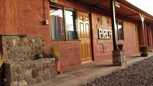 a red brick building with a fire sign on the door at Pirca Hostal in San Pedro de Atacama