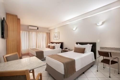 a hotel room with two beds and a table at Plaza Inn American Loft in Sao Paulo