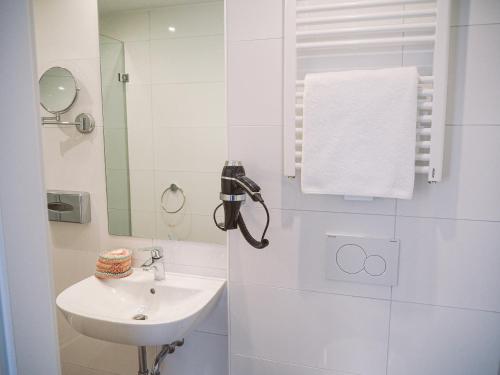 W białej łazience znajduje się umywalka i lustro. w obiekcie Tante ALMA's Mülheimer Hotel w mieście Mülheim an der Ruhr