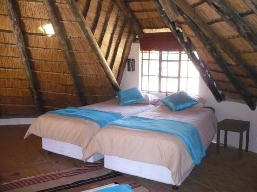 two beds in a room with wooden ceilings at Mafube Mountain Retreat in Fouriesburg