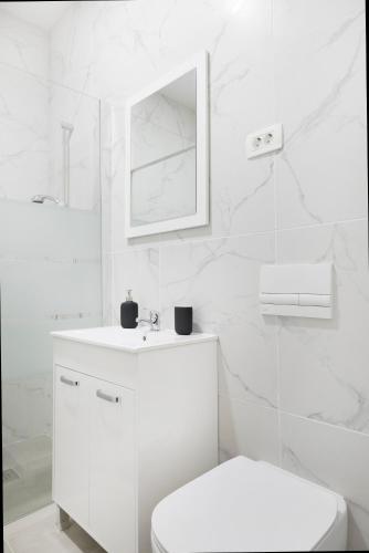 a white bathroom with a toilet and a mirror at Cozy apartments in Ljubljana