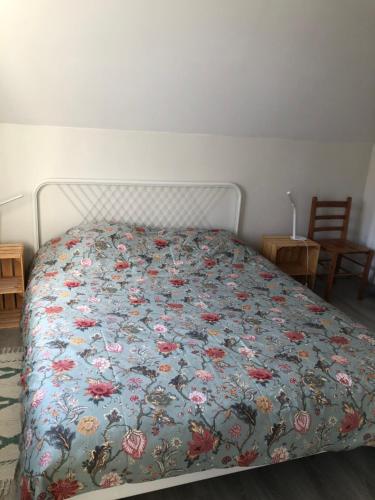 a bedroom with a bed with a floral bedspread at Appartement lumineux et calme in Jodoigne