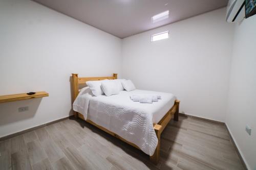 卡利的住宿－Hotel Alameda Plaza，一间卧室配有一张铺有木地板的白色床单。