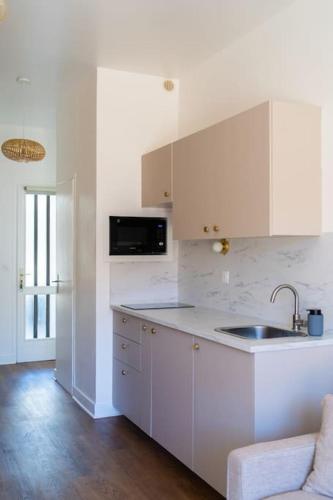 une cuisine blanche avec un évier et un micro-ondes dans l'établissement Studio tout confort à deux pas de l'océan - Wifi, à Biscarrosse