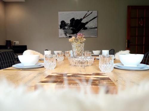 une table en bois avec des verres, des assiettes et un vase dans l'établissement Gite le pré des cerfs II, à La Bresse