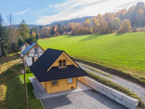 a small house with a black roof on a field at Antosiowy domek in Wisła
