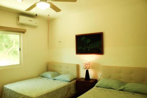 a bedroom with two beds and a window and a fan at Rodas villas contiguas para la vacación perfecta in San Bruno