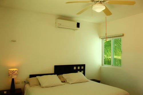 a bedroom with a bed with a ceiling fan and a window at Rodas villas contiguas para la vacación perfecta in San Bruno