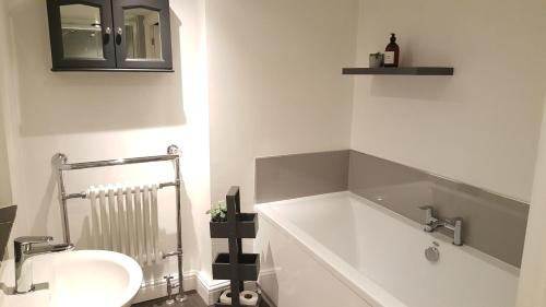 een witte badkamer met een wastafel en een spiegel bij Mill Cottage Modern Boutique Cosy Home in Lake District Village near Scafell in Gosforth