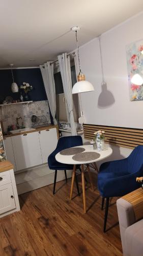 - un salon avec une table et deux chaises bleues dans l'établissement Apartament Przy Parku, à Nałęczów