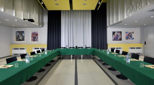 a long conference room with green tables and chairs at Hotel Carlton in Ferrara