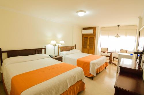 a hotel room with two beds and a table at Hotel Majestic in Barranquilla