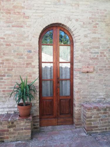 a wooden door on a brick wall with a potted plant at Podere Sant'Antonio in Buonconvento