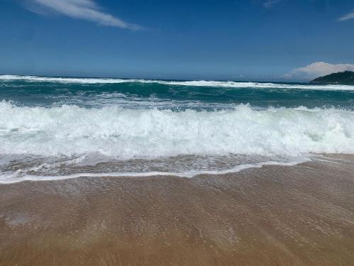 a beach with a wave in the ocean at Studios Aromas do Campeche - Floripa in Florianópolis