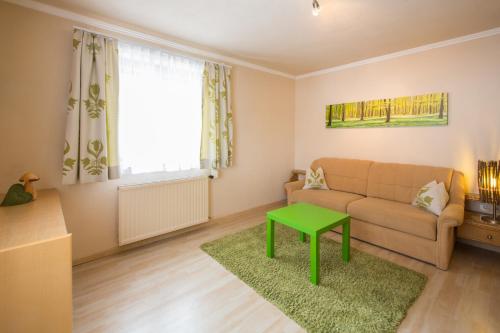 a living room with a couch and a green table at Pension Anna in Sankt Leonhard im Pitztal