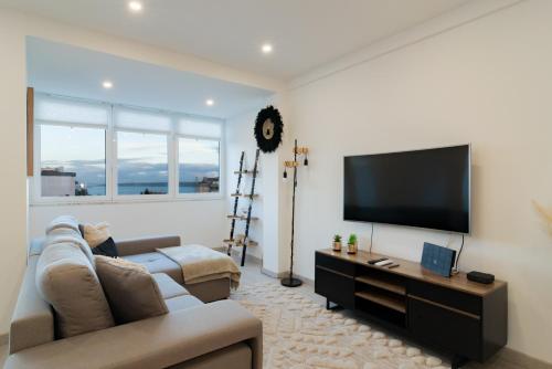a living room with a couch and a flat screen tv at Stylish Apartment W/ River View by LovelyStay in Oeiras