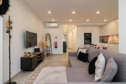 a living room with a gray couch and a kitchen at Stylish Apartment W/ River View by LovelyStay in Oeiras