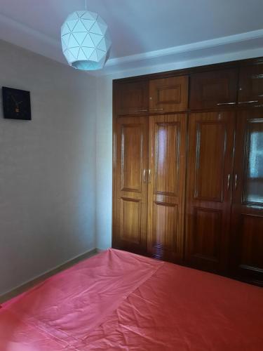 a room with a pink sheet on the floor and wooden cabinets at APPARTEMENT AMIRA iFRANE in Ifrane