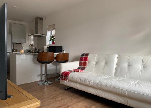 a living room with a white couch and a kitchen at Newly built modern flat at London Gants Hill Station near Ilford in Wanstead