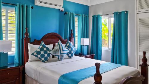 ein blaues Schlafzimmer mit einem Bett mit blauen Wänden und Fenstern in der Unterkunft Casa Maurice Ocho Rios Villa in Ocho Rios