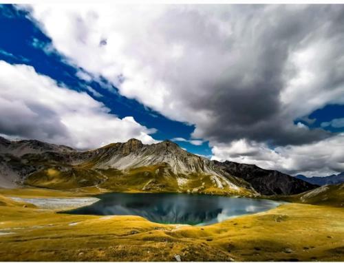 a mountain with a lake in the middle of a field at Haus Greiner in Nauders
