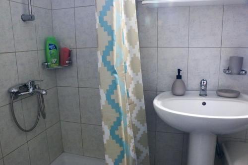 a bathroom with a shower with a sink and a shower curtain at Villa Evgenia(Leonidas) in Ierissos