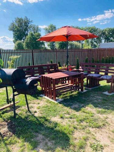 a picnic table with a red umbrella and benches at Vila Mária Rapovce in Rapovce