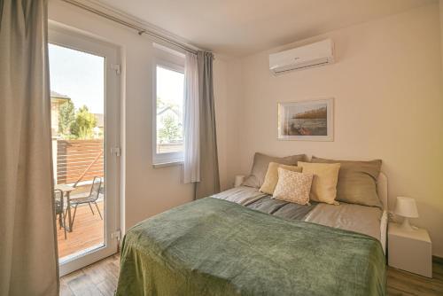 1 dormitorio con 1 cama y puerta a un balcón en Happy Apartments, en Balatonlelle