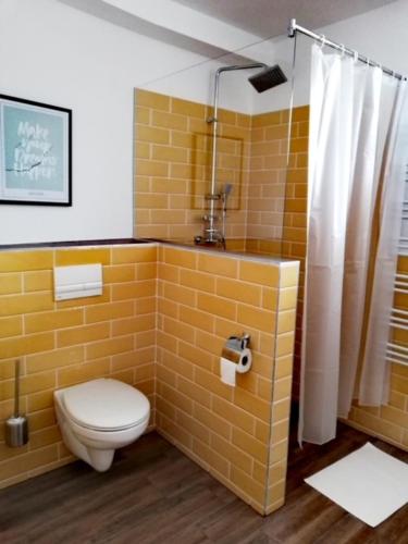 a yellow bathroom with a toilet and a shower at Happy Apartments in Balatonlelle