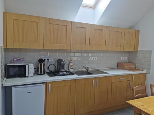 a kitchen with wooden cabinets and a sink and a microwave at Breier Farm - Tanya Panzió in Pomáz