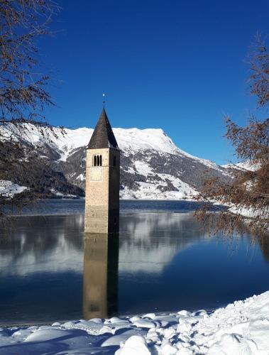 a tower in the middle of a lake in the snow at Haus Greiner in Nauders