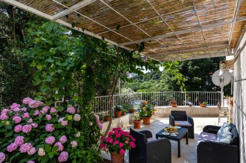 a patio with flowers and chairs and a pergola at Studio and Room Lena in Dubrovnik