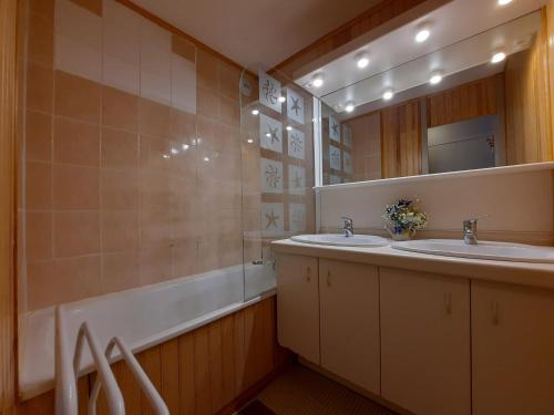 uma casa de banho com 2 lavatórios, uma banheira e um espelho. em Appartement Les Menuires, 2 pièces, 5 personnes - FR-1-452-125 em Les Menuires