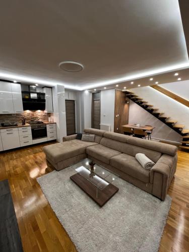 a living room with a brown couch and a staircase at Inverno Apartments Bjelašnica in Bjelašnica