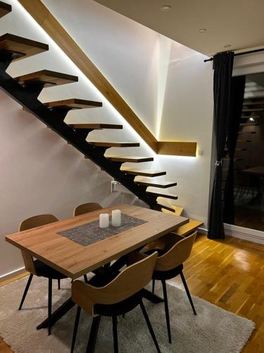 a dining room with a wooden table and stairs at Inverno Apartments Bjelašnica in Bjelašnica