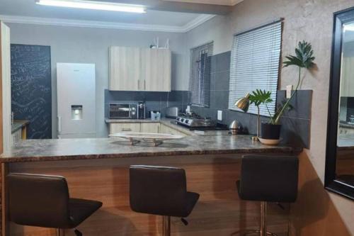 a kitchen with a large counter with chairs in it at The Minimalist Hide away in Benoni